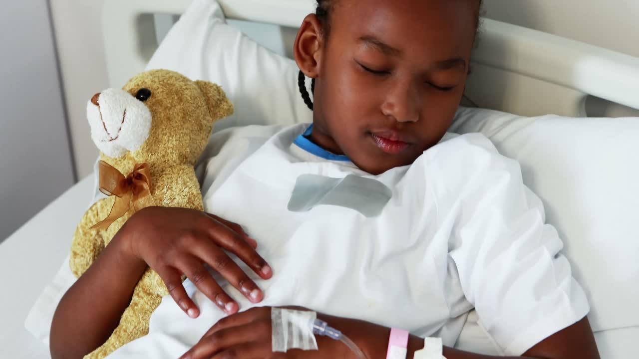 Sick girl resting with teddy bear on bed
