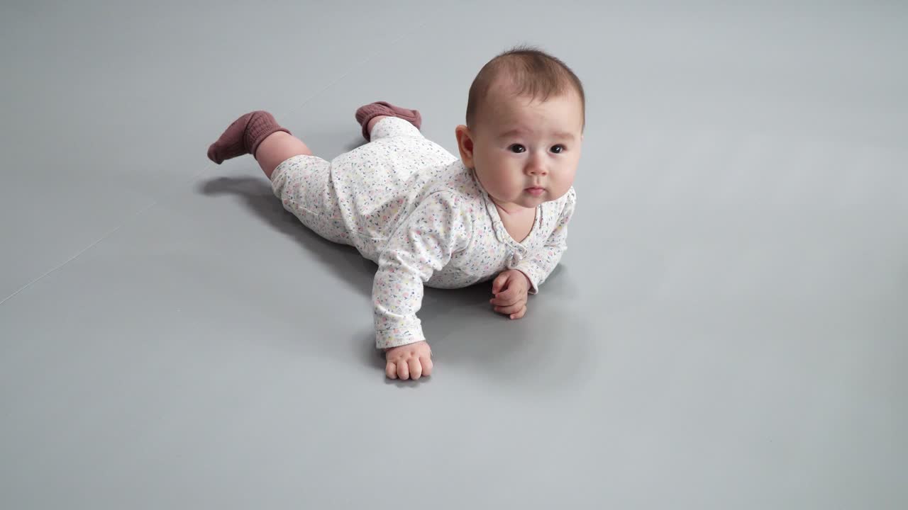 bebé activo en general impreso y calcetines marrones rodando y acostado boca abajo