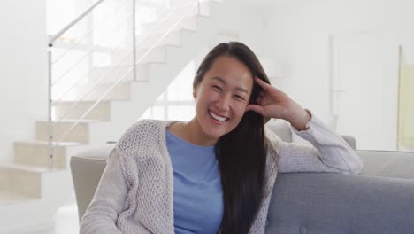 집에서 소파에 앉아 있는 행복한 아시아 여성