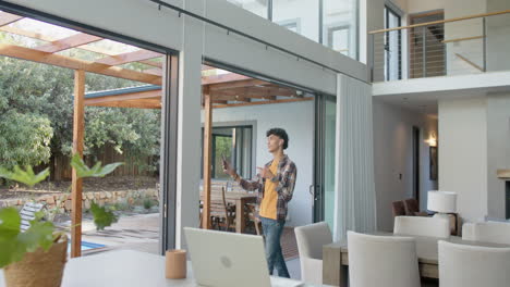 opening sliding glass door, teenage boy enjoying fresh air in modern home with laptop