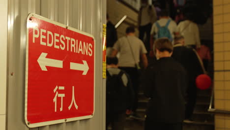 static shot of pedestrians walking in and out of the subway in an asian city