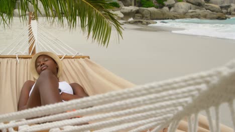 vista frontal de una mujer afroamericana durmiendo en una hamaca en la playa 4k