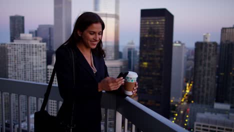 una mujer de negocios hispana usando un teléfono inteligente bebiendo café en el techo