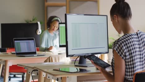 diverse business people sitting at table and using computers at office