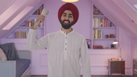 hombre indio sikh feliz usando dinero como ventilador