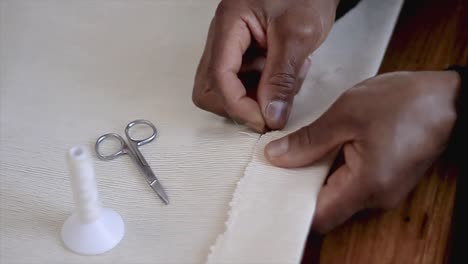 hand sewing with needle and thread with fabric on a table stock video