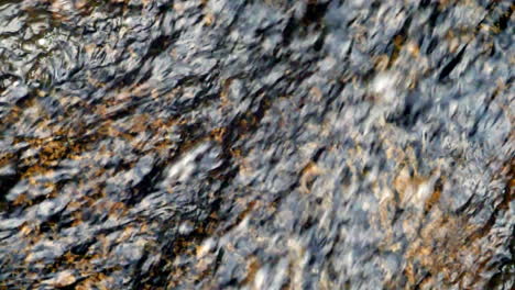 tight shot of water flowing over a rock shot in slow motion