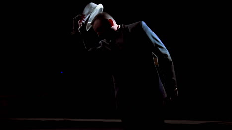 actor man on a stage. dark silhouette of a man wearing suit performing on a scene in theatre at spotlight. view from the stage.