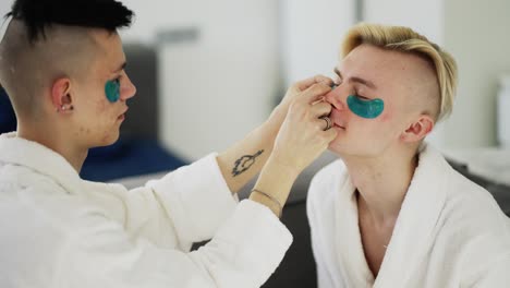 pareja gay divirtiéndose usando parches en los ojos en bata de baño