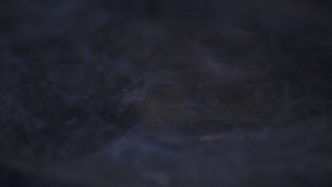 liquid stain dripping into a basin of water forming a circular pattern on the surface - closeup shot