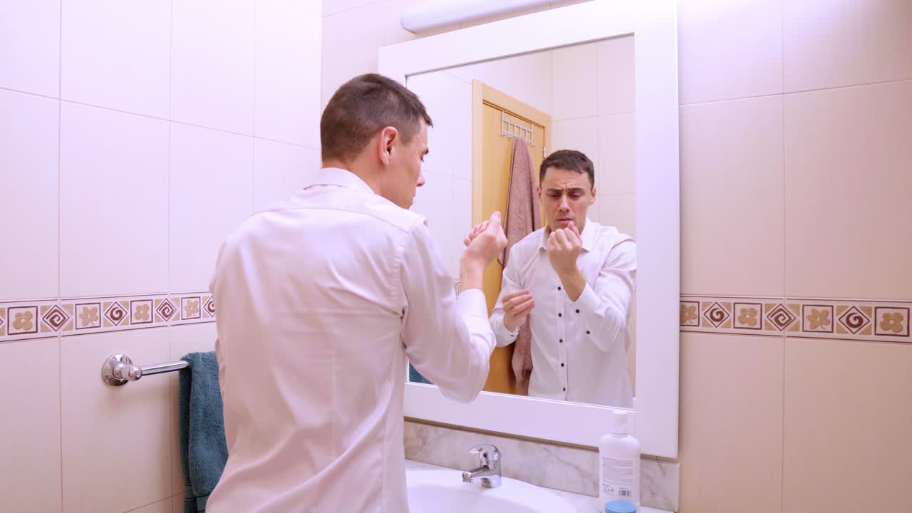 욕실 거울에서 머리카락이 빠지는 것을 확인하는 남자