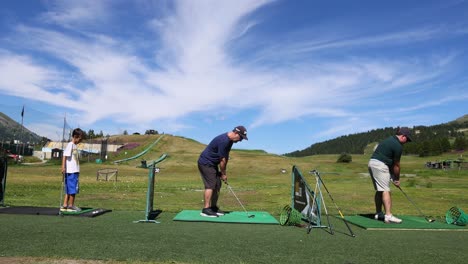 three people practicing golf on a sunny day