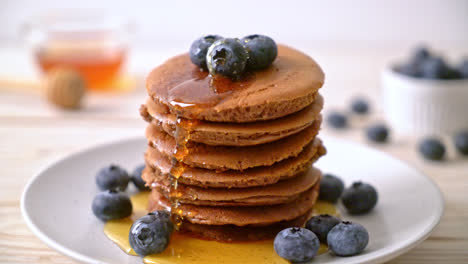 chocolate-pancake-stack-with-blueberry-and-honey-on-plate