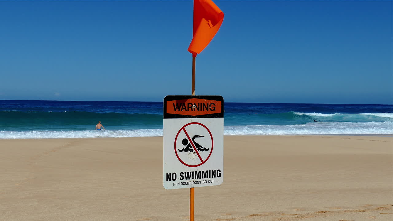 imágenes de un cartel de advertencia de no nadar publicado en una playa en la costa norte de oahu, hawaii