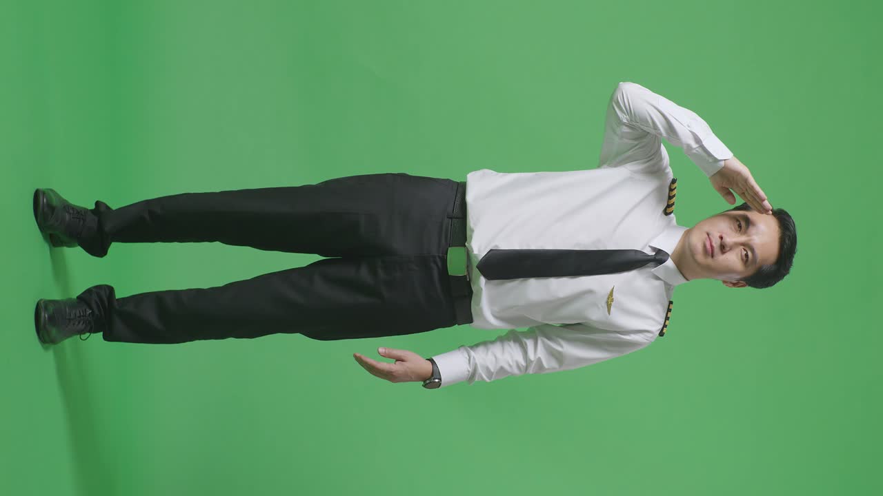 아시아 남성의 몸이 가득한 조종사는 존경스럽고, 녹색 스크린 배경 스튜디오에 서서 인사를합니다.