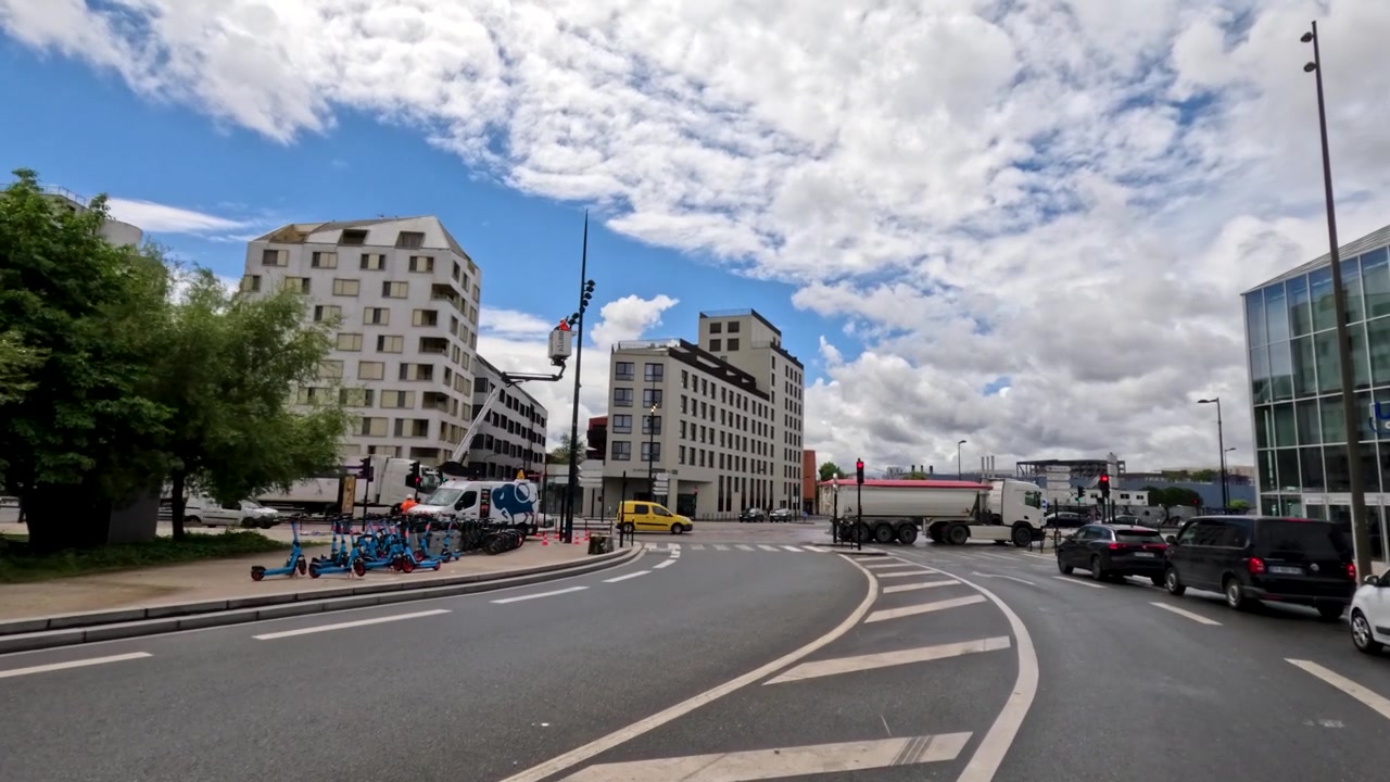 Eine Weitwinkel-Kamerafahrt bewegt sich durch eine moderne städtische Kreuzung unter einem dramatischen Himmel