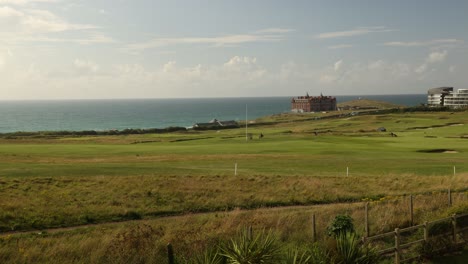 Tiro-De-Lapso-De-Tiempo-De-Gente-Jugando-Al-Golf-En-La-Costa-De-Newquay-Con-Un-Hotel-Detrás