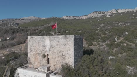 castle wall and flag in the middle of the mountain, drone view, belenkeşlik castle, turkey