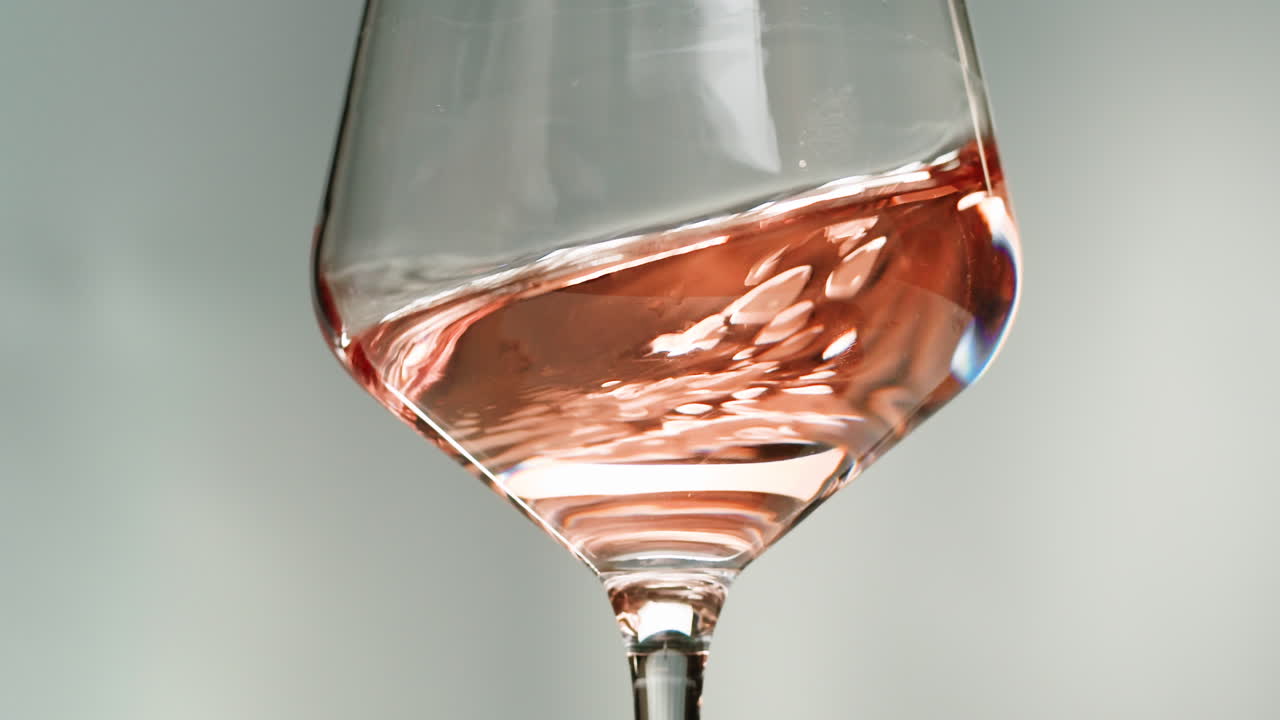 Rosé, orange eller hvidvinsflaske og glas mod en solnedgang i en fredfyldt vingård, hvor der hældes økologisk naturvin op. Skål, hænder med vinglas, der drikker alkohol