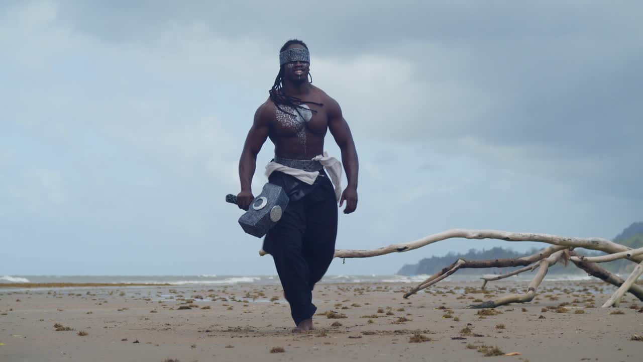 A muscular, dark-skinned man, authentically portraying Nekharis in cosplay, graces a tropical beach