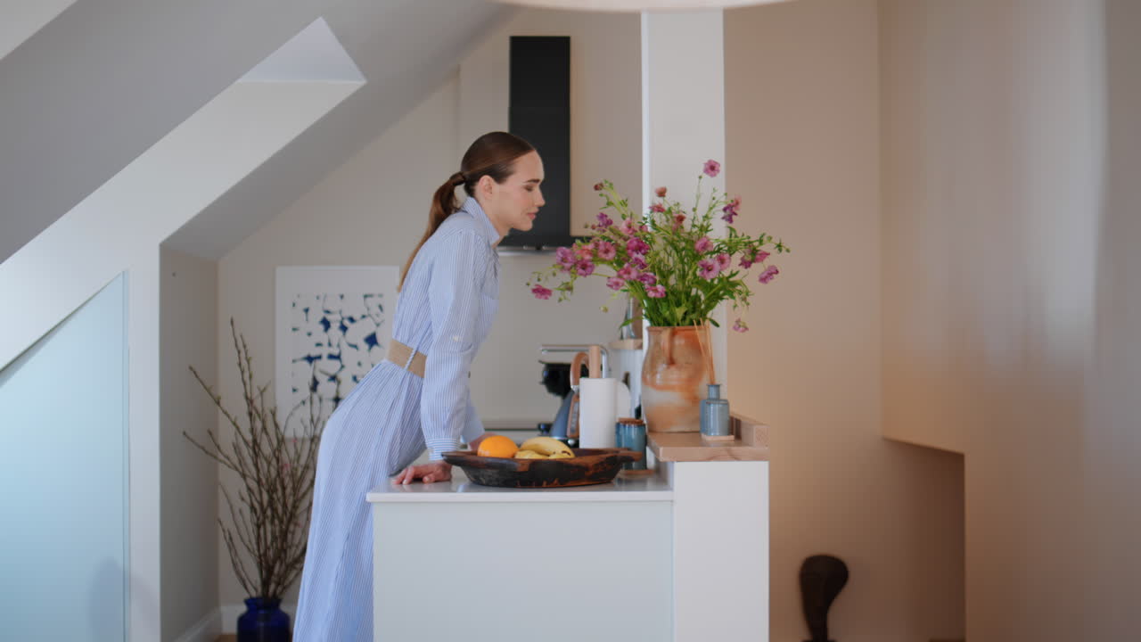 Casalinga che mette dei fiori in un vaso per decorare la casa. Donna che annusa un bouquet