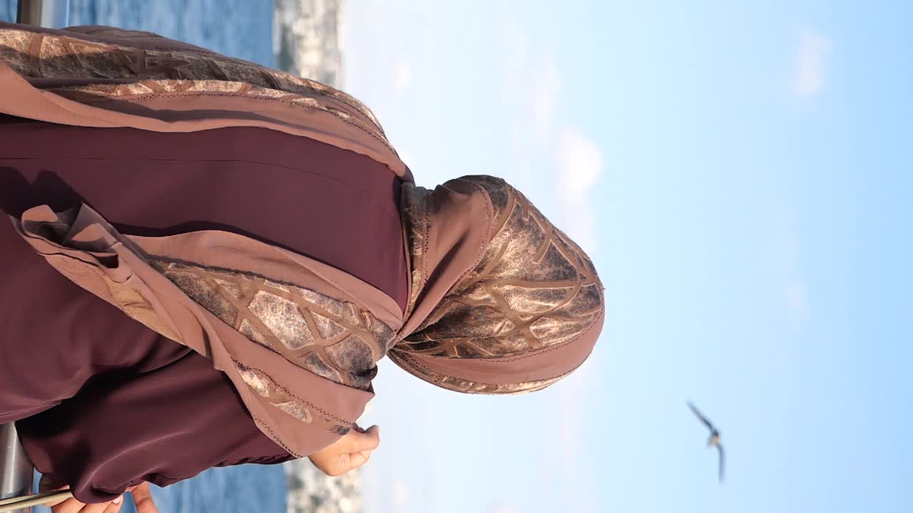 Donna musulmana con hijab che guarda il panorama sul mare