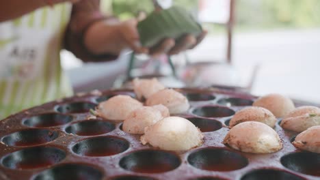 closeup cooking traditional thai street food sweet dessert khanom krok, coconut milk pancake mix sugar and flour on process with spring onions on top