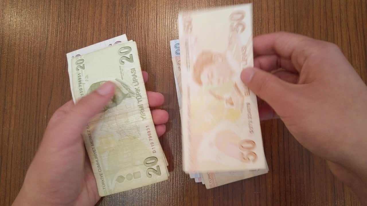 Teenager počítající náhodné množství bankovek turecké liry s portréty slavných tureckých osobností z oblasti vědy, literatury a hudby.