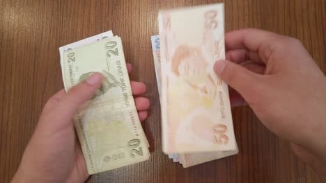 un adolescente contando una cantidad aleatoria de billetes de lira turca con retratos de figuras turcas famosas de la ciencia, la literatura y la música