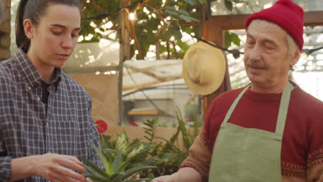 un vendedor sénior discutiendo plantas con los clientes en una tienda de flores