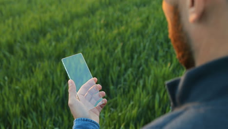 close-up view of caucasian man hands tapping on glass in the green field