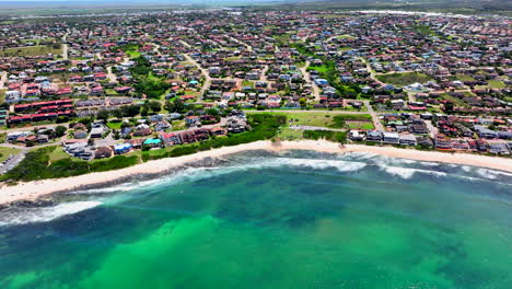 South-Africa-JBAY-Jeffreys-Bay-aerial-drone-town-home-buildings-most-stunning-white-sand-beach-epic-surf-wave-aqua-blue-rugged-reef-coastline-daytime-WSL-Corona-Open-Supers-Boneyard-summer-back-pan-up