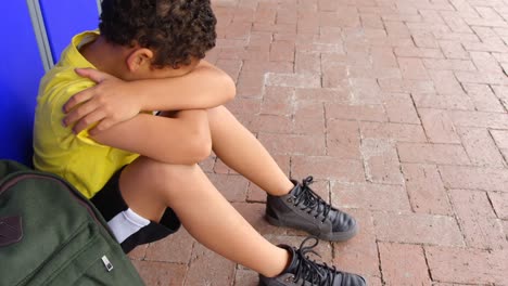 Side-view-of-schoolboy-sitting-alone-on-floor-in-the-corridor-4k