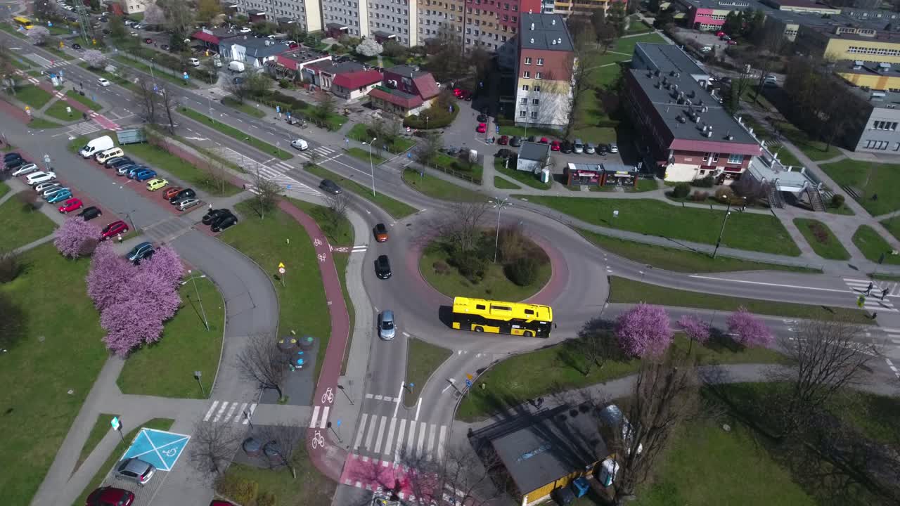 rotonda en el centro de la ciudad con coches y un autobús amarillo conduciendo en ella, durante el verano en polonia