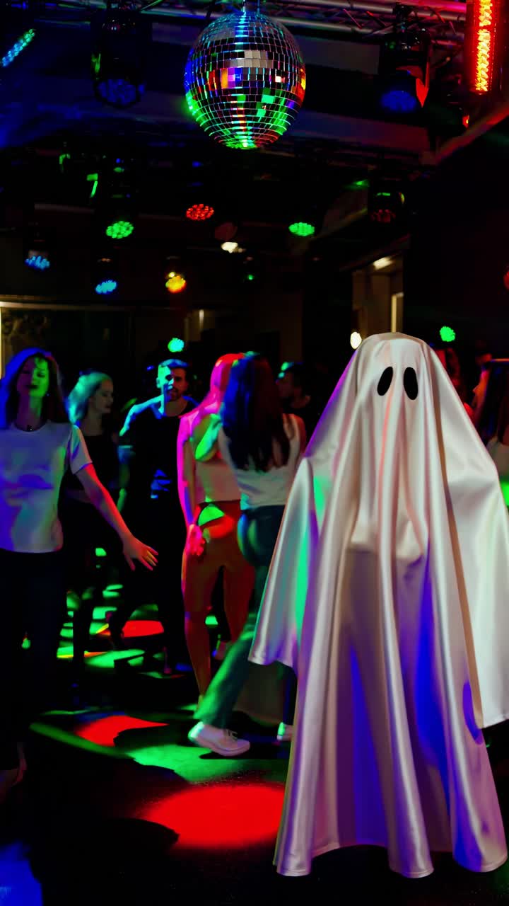 Halloween partygoers wearing ghost costumes dancing energetically under ...