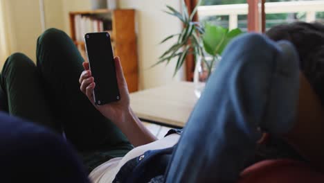 Mujer-Caucásica-Usando-Un-Teléfono-Inteligente,-Tumbada-En-Un-Sofá-En-Casa