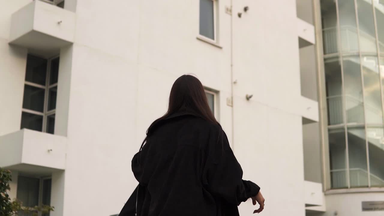 검은 재킷을 입은 브루네트 모델은 스페인어로 보이는 환경 plm 트리 슬로우 모션의 새로운 영역을 궁금해하고 있습니다.