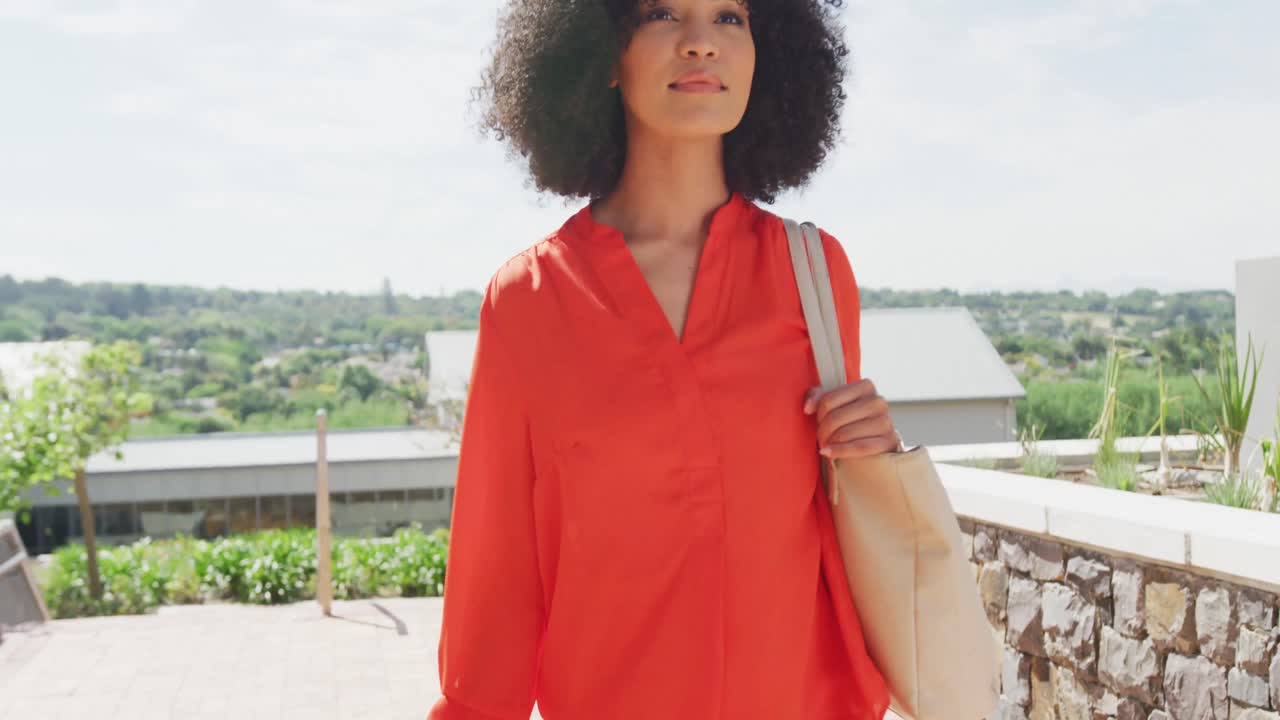Imprenditrice afroamericana felice che cammina e tiene in mano la borsa, al rallentatore