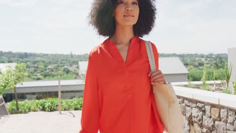 Happy-african-american-businesswoman-walking-and-holding-bag,-slow-motion