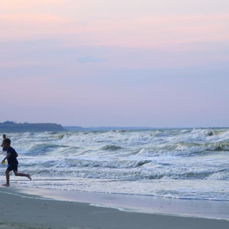 little boy playing with water in the seashore. cute child enjoys with his toy near the water in the evening. happy childhood.
