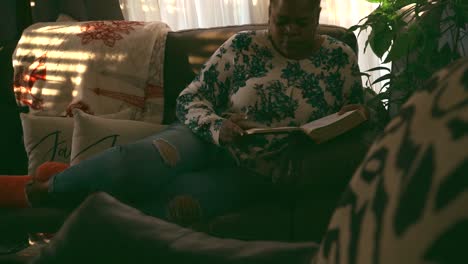 black woman relaxing on couch reading bible