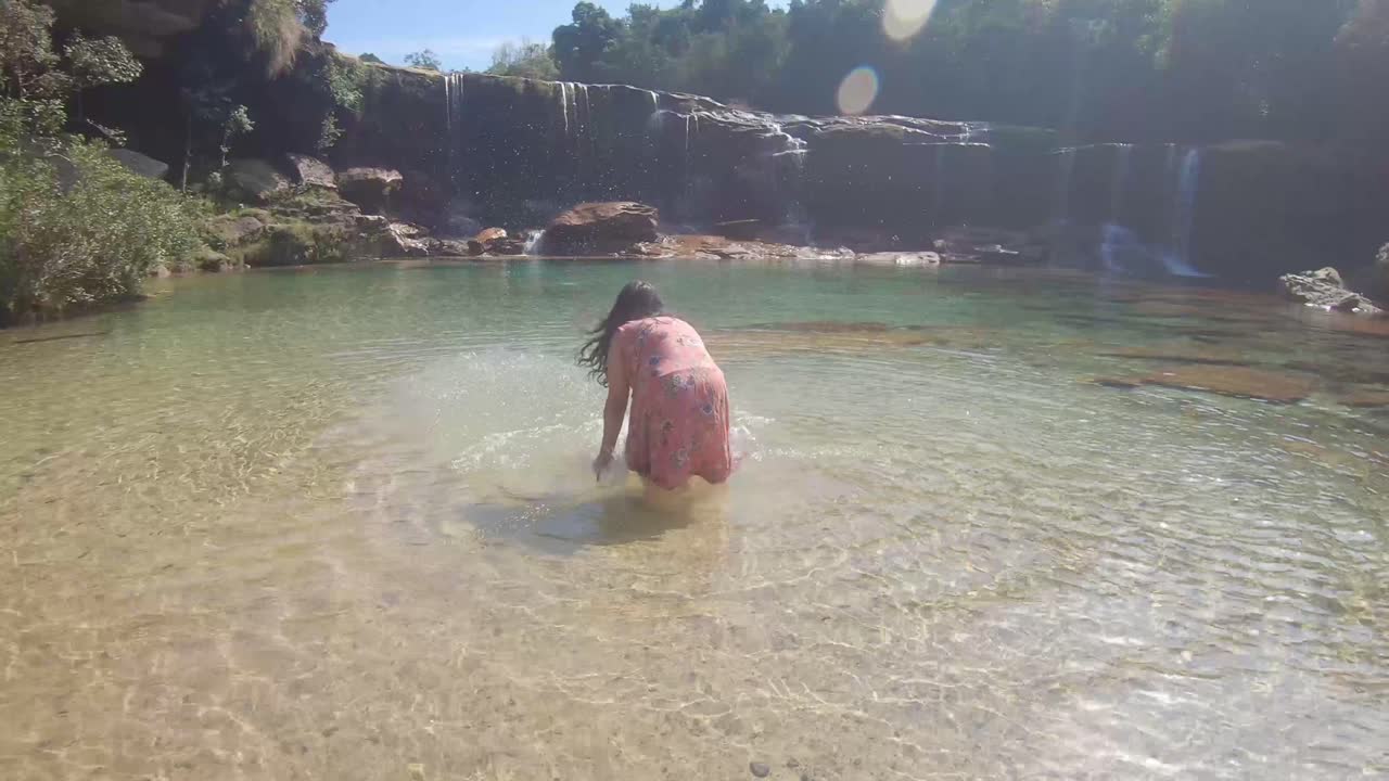 Jeune fille profitant d'une cascade le matin en plan frontal