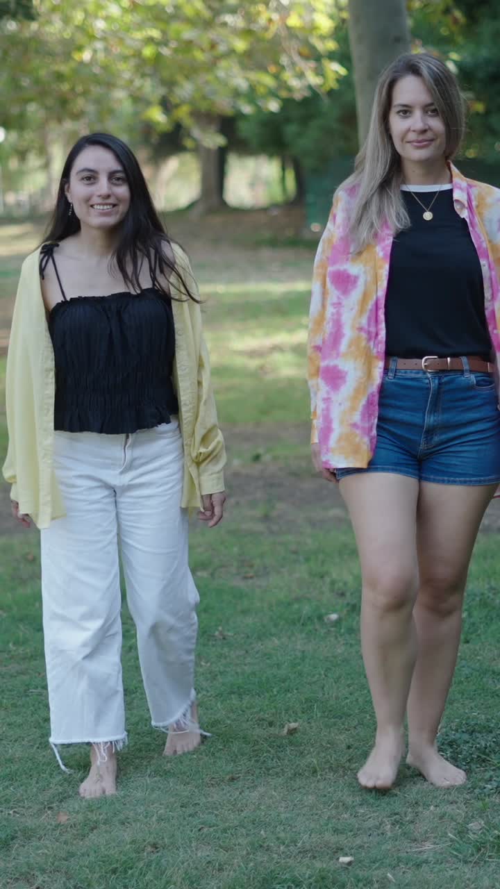 Two women walking barefoot in the park