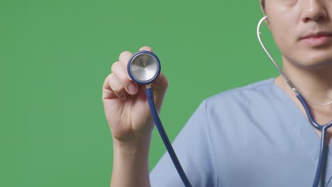 close up of male doctor's hand holding a stethoscope on green screen background in the hospital