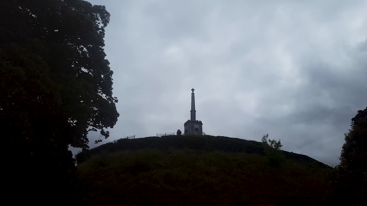A time lapse of grey clouds passing over a monument in Canterbury, Kent.  The monument is on top of a steep hill.