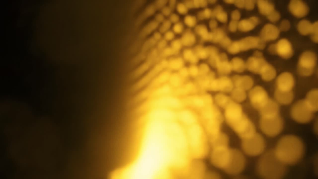 This captivating moment captures golden light reflecting off a textured surface, creating a mesmerizing, warm ambiance during sunset. The interplay of color and texture is enchanting.