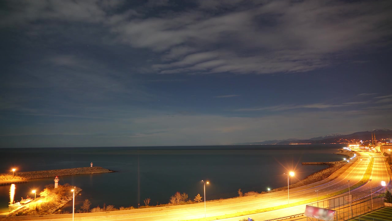 Lapso de tiempo de carretera costera y faro de noche