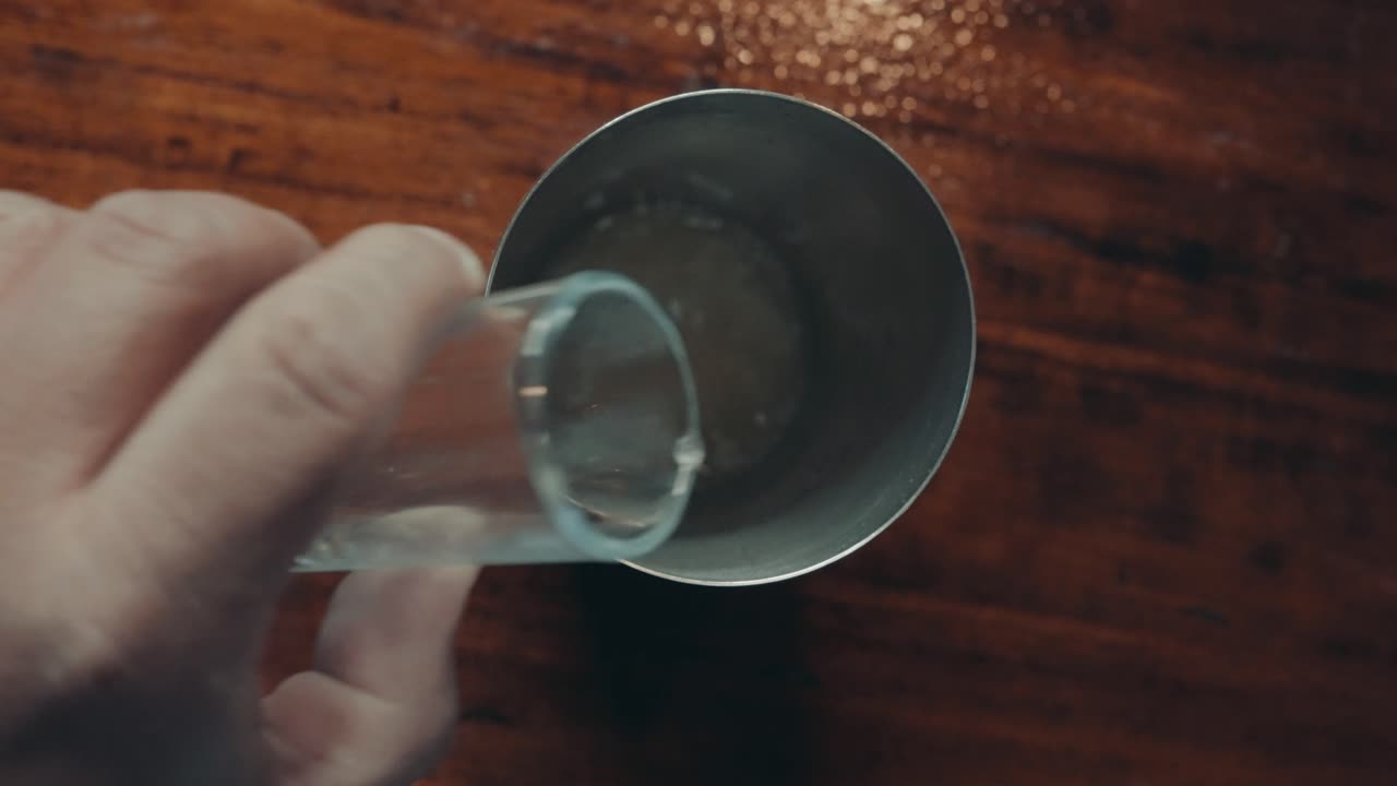 레몬 주스를 금속 칵테일 셰이커에 붓고, 위에서 아래로 보기를 닫습니다.