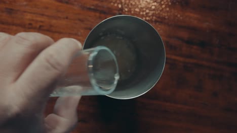 verter jugo de limón en una coctelera de metal, vista de arriba hacia abajo de cerca