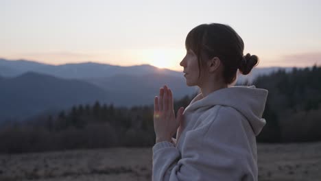 woman meditating at sunset in the mountains